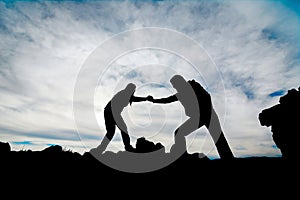 Silhouette of helping hand between two climber